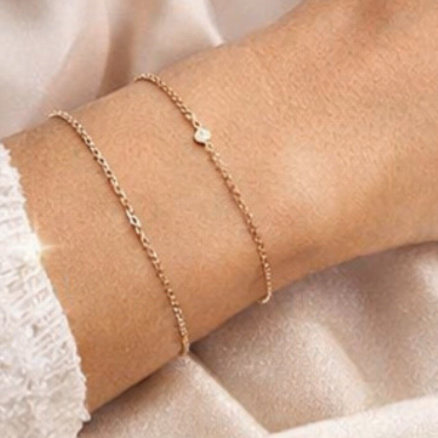 Delicate gold bracelets on skin in soft light
